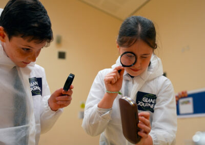 Two children in lab suits holding equipment